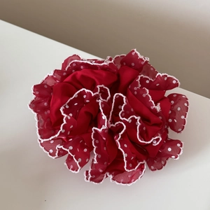 Détail d'un chouchou en mousseline rouge à pois avec bords festonnés et effet plissé