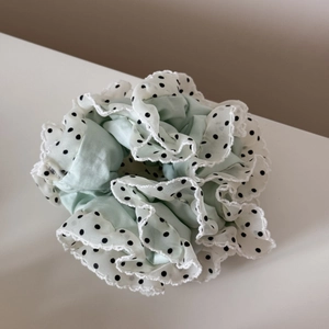 Détail d'un chouchou vert menthe avec bordure en dentelle blanche et pois noirs