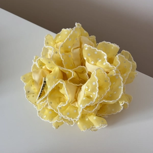 Détail de chouchou en organza jaune à pois avec volants superposés et bordure ondulée