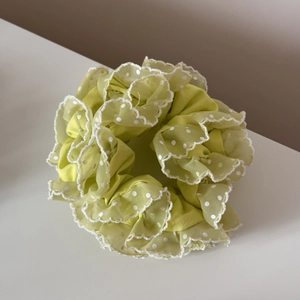 Détail du chouchou en organza vert clair à pois avec des bords à volants blancs