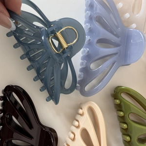 Detail of five butterfly hair claws in various matte colors with golden metal spring