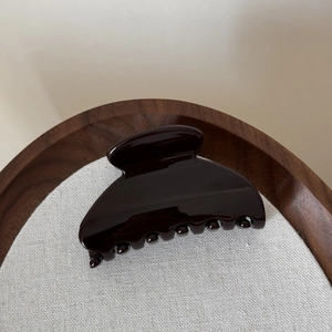 Gros plan d'une pince à cheveux brillante sur lin dans une boîte à bijoux en bois