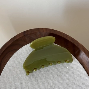 Vue détaillée de la pince à cheveux en forme d'éventail vert herbe sur plateau bois