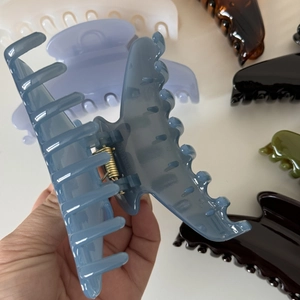 Macro detail of large glossy shark clip showing metal spring and sturdy claw teeth