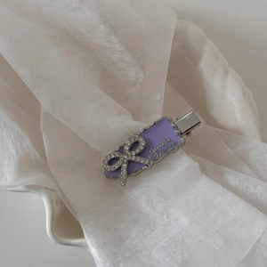 Détails de la barrette en émail violet avec nœud en strass et bordure argentée ondulée