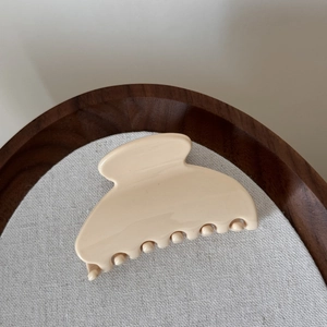 Détail d'une pince à cheveux crème élégante avec finition brillante sur un tissu