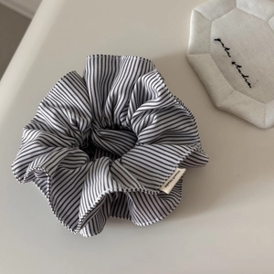 Détail d'un chouchou en tissu rayé avec étiquette faite main et texture plissée