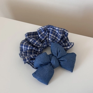 Close-up of blue plaid cotton scrunchie with denim bow texture and stitching details
