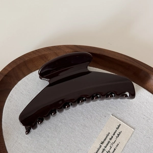 Glossy large dark coffee hair claw clip shown on a rustic wooden tray with linen