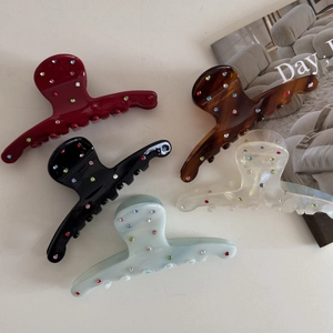 Five assorted acetate hair claws with multi-colored rhinestones on white background