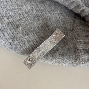 Détail de la pince à cheveux argentée pailletée avec strass en cœur et inscription Love