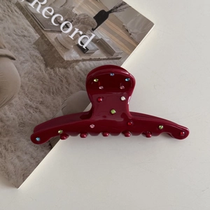 Detail of burgundy acetate hair claw clip with colorful rhinestones and glossy finish