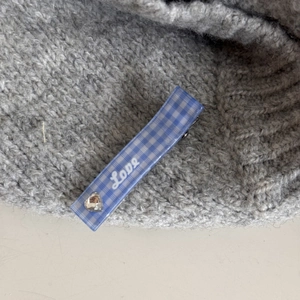 Détail de la pince à cheveux à carreaux bleus avec texte Love et strass en forme de cœur