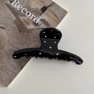 Detailed view of a black acetate hair claw clip decorated with multi-colored rhinestones