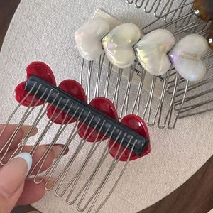 Detailed view of red and white heart acetate hair combs on a beige linen background