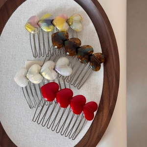 Detail view of heart-shaped cellulose acetate hair side combs in four stylish finishes