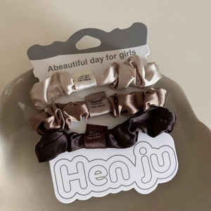 Detailansicht von drei Satin-Haargummis in Erdtönen auf einem minimalistischen Keramikteller