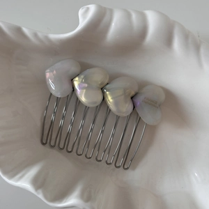 Detail of acetate heart hair comb with iridescent finish and silver metal teeth