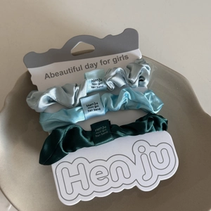Dreiteiliges Satin-Haargummi-Set in Silber, Blau und Grün auf einer weißen Displaykarte