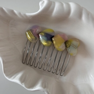 Close-up of marble acetate heart charms on a silver metal hair comb accessory