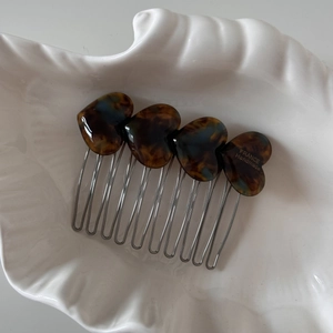 Detail of tortoise shell heart hair comb with silver metal teeth on shell tray