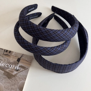 Close-up of blue and black plaid sponge headbands with handmade woven label details
