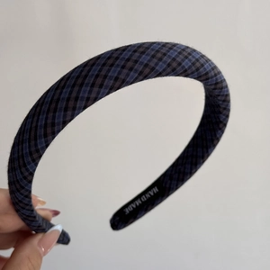 Close-up of blue and black plaid headband with Hand Made label on the inner side