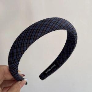 Close-up of the vintage blue plaid sponge headband with a black handmade woven label