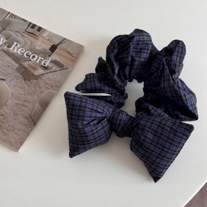 Detail of blue and black plaid bow scrunchie with high-quality woven fabric texture