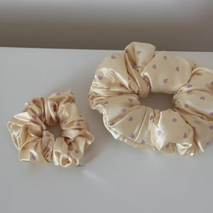 Close-up of beige satin scrunchies with purple heart patterns in two different sizes