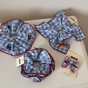 Detail of blue gingham hair scrunchies set with cherry embroidery and red piping edges