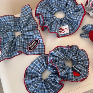 Detail von blau-weiß karierten Haargummis mit roter Paspel und Atlanta-Stickerei