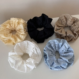 Flat lay of five striped translucent hair scrunchies in cream, black, khaki, white, and blue