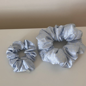 Detail view of light blue satin scrunchies with white polka dots in two varied sizes