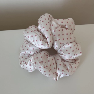 Close-up of white satin scrunchie with pink polka dots showing smooth texture and volume