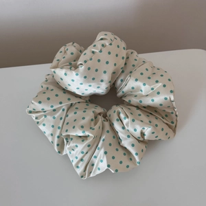 Detailed close-up of cream satin scrunchie with mint green polka dots and silky texture