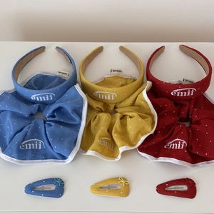 Détail de chouchous et de serre-têtes à pois colorés avec broderie emii et barrettes