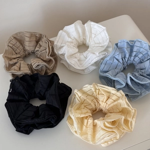 Set of five striped fabric scrunchies in black, white, and pastel tones on a flat surface