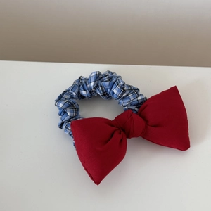 Detailansicht des rot-blau karierten Haargummis mit Schleife und feiner Bestickung
