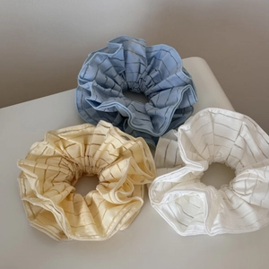 Detail view of large striped scrunchies in translucent blue, yellow, and beige fabrics
