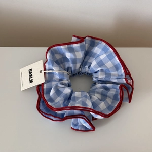 Close-up of blue plaid scrunchie with red scalloped edges and sweet cherry embroidery