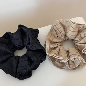 Detailed macro view of large striped scrunchies in black and beige mesh fabric