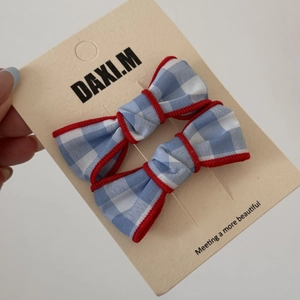 Detail of blue plaid bow hair ties with red wavy edges and sweet cherry embroidery