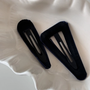 Detail view of navy blue polka dot fabric hair clips in oval and triangle shapes