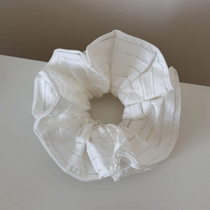 Detail shot of white striped mesh scrunchie with soft pleated texture for hair
