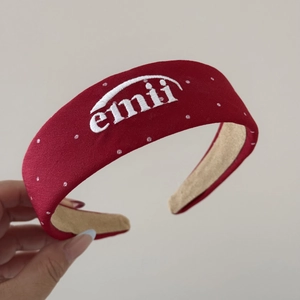 Détail d'un bandeau en tissu rouge à pois blancs avec un motif brodé emii chic