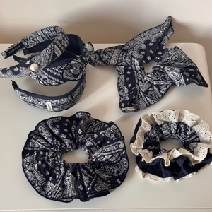 Detail of navy blue paisley hair accessories with white lace trim and pearl accents