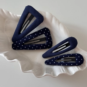 Set of navy blue fabric hair clips with polka dot patterns on a white ceramic tray