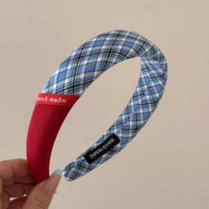 Detail eines rot-blau karierten Haargummis mit handgefertigtem Etikett auf Stoff