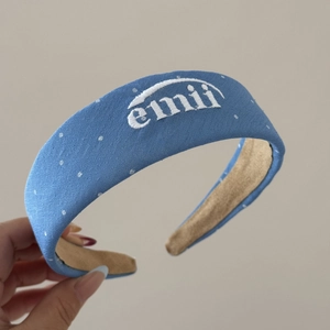Gros plan d'un bandeau bleu texturé avec pois blancs et broderie emii élégante